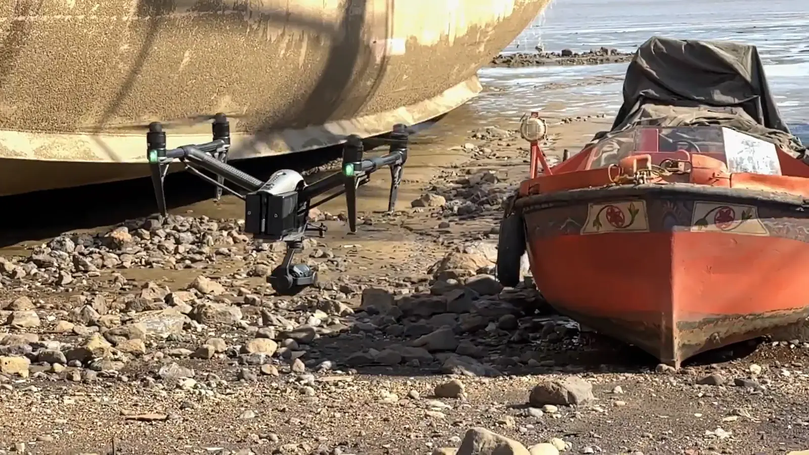 Drone scanning a boat on a rocky beach
